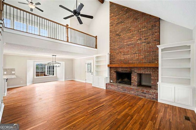 unfurnished living room featuring a brick fireplace, baseboards, and wood finished floors