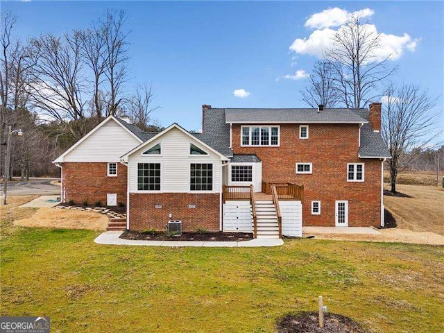 rear view of property with a yard, a chimney, stairway, and brick siding