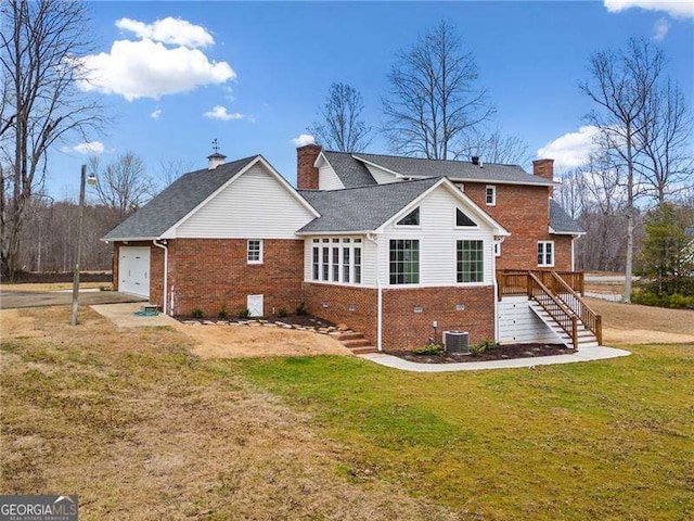 back of property with a garage, a yard, brick siding, and a chimney