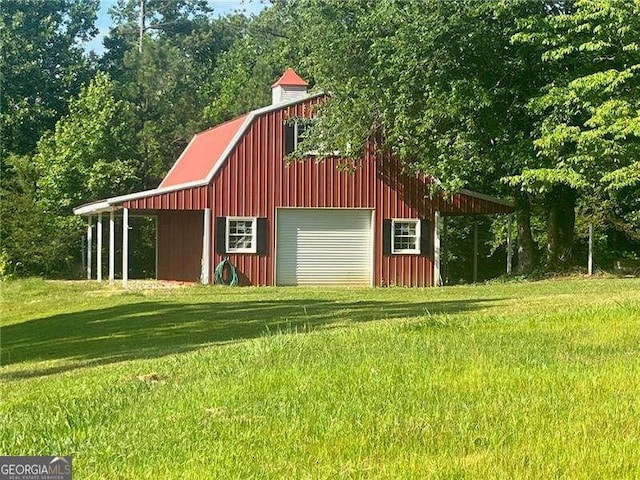 view of barn featuring driveway and a lawn