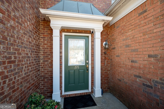 doorway to property with a standing seam roof, metal roof, and brick siding