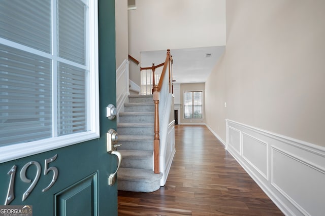 entryway with a decorative wall, dark wood-style flooring, visible vents, stairs, and wainscoting