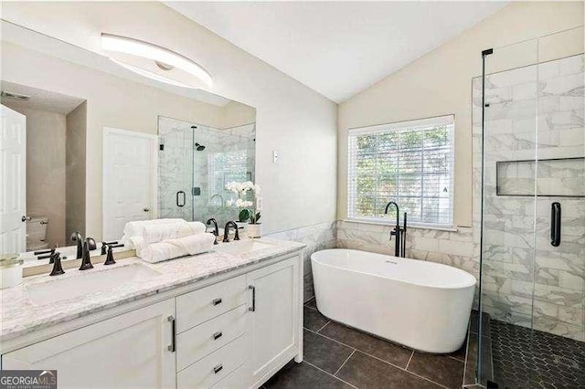 full bathroom with double vanity, lofted ceiling, a freestanding bath, a stall shower, and tile patterned floors