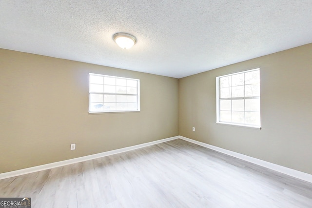 spare room with a wealth of natural light, light wood-style flooring, and baseboards