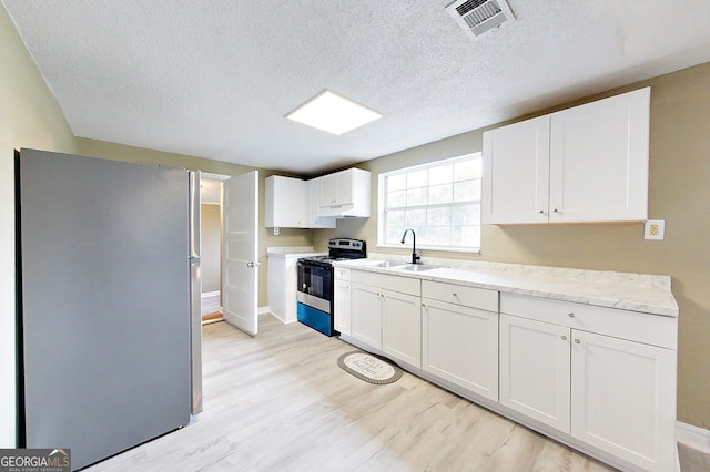 kitchen with light countertops, visible vents, appliances with stainless steel finishes, white cabinets, and a sink