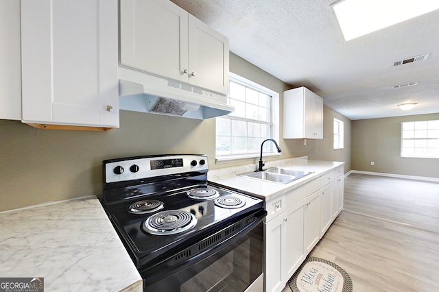 kitchen featuring electric range, light countertops, under cabinet range hood, white cabinetry, and a sink