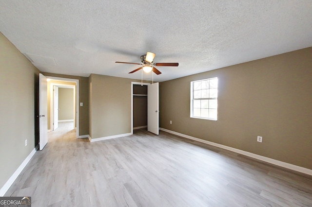 unfurnished bedroom featuring a textured ceiling, light wood-style flooring, a ceiling fan, baseboards, and a closet