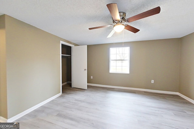 unfurnished bedroom featuring light wood finished floors, baseboards, and a textured ceiling