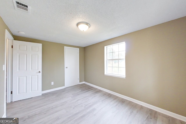 unfurnished bedroom with light wood-type flooring, baseboards, visible vents, and a textured ceiling