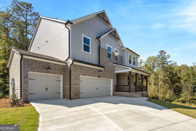 view of front of home with brick siding, covered porch, concrete driveway, an attached garage, and board and batten siding