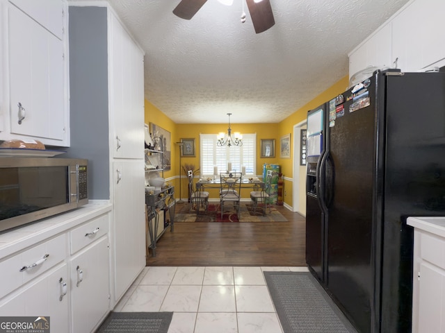 kitchen featuring light countertops, black refrigerator with ice dispenser, stainless steel microwave, and white cabinets