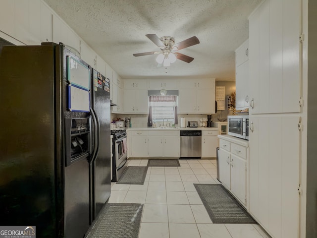 kitchen with stainless steel appliances, light countertops, a sink, and white cabinetry