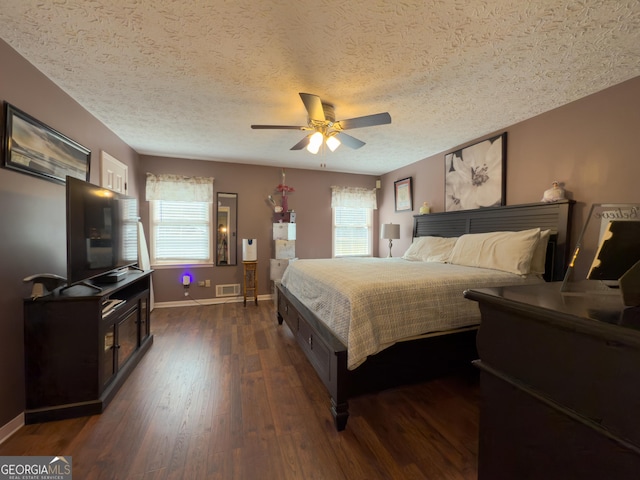 bedroom featuring dark wood-type flooring, visible vents, baseboards, and a ceiling fan