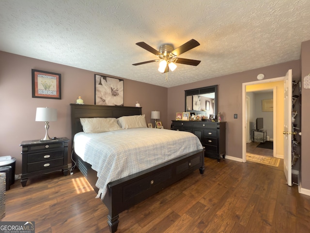 bedroom with a ceiling fan, a textured ceiling, baseboards, and dark wood-style flooring