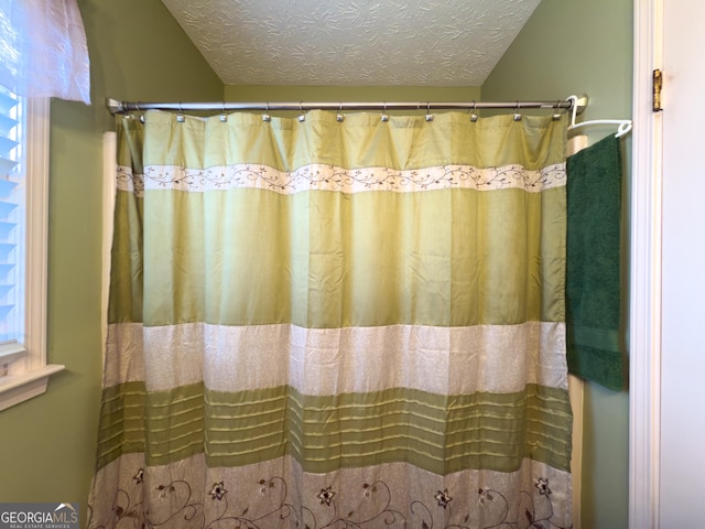 full bath featuring curtained shower and a textured ceiling