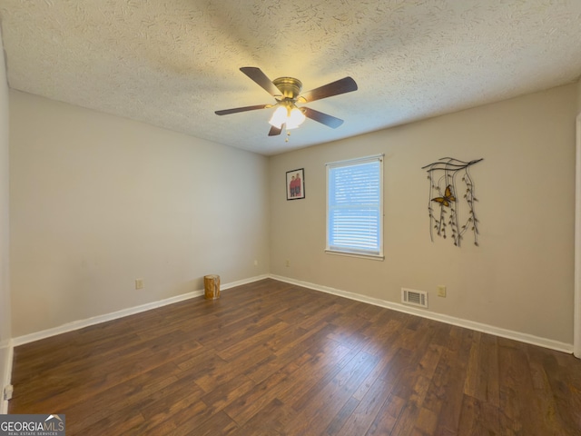 empty room with dark wood-style floors, ceiling fan, visible vents, and baseboards