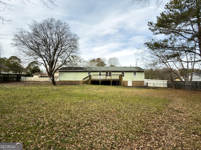 rear view of property featuring a fenced backyard, a yard, and a wooden deck