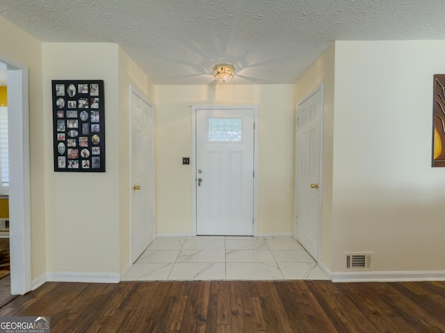 entrance foyer featuring marble finish floor, visible vents, a textured ceiling, and baseboards