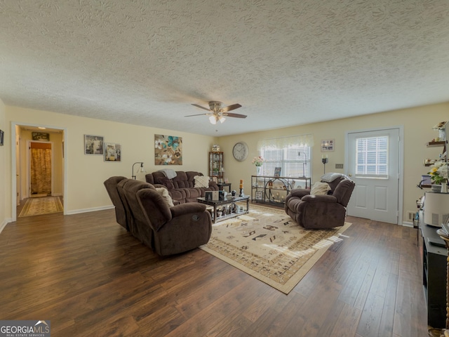 living room with dark wood-type flooring, ceiling fan, a textured ceiling, and baseboards