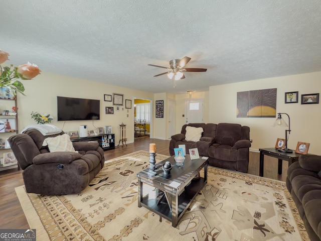 living area featuring baseboards, a textured ceiling, a ceiling fan, and wood finished floors