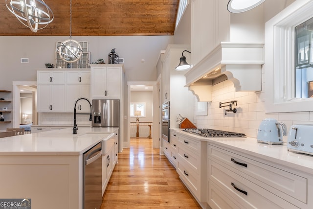 kitchen with hanging light fixtures, white cabinetry, stainless steel appliances, and light countertops