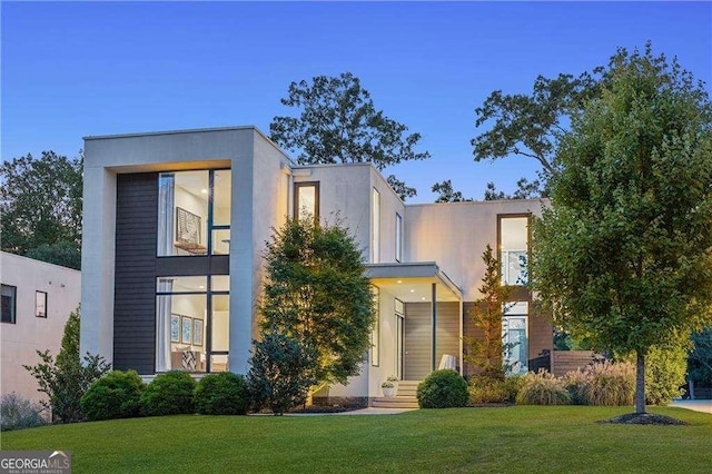 contemporary home featuring stucco siding and a front lawn