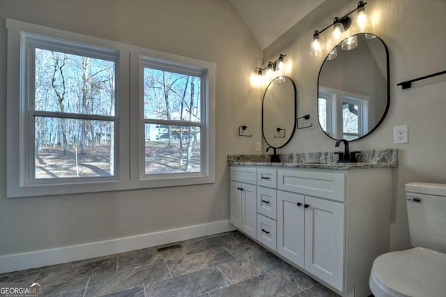 full bath featuring double vanity, visible vents, baseboards, lofted ceiling, and a sink