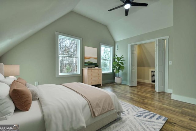 bedroom featuring dark wood-style floors, vaulted ceiling, a ceiling fan, and baseboards