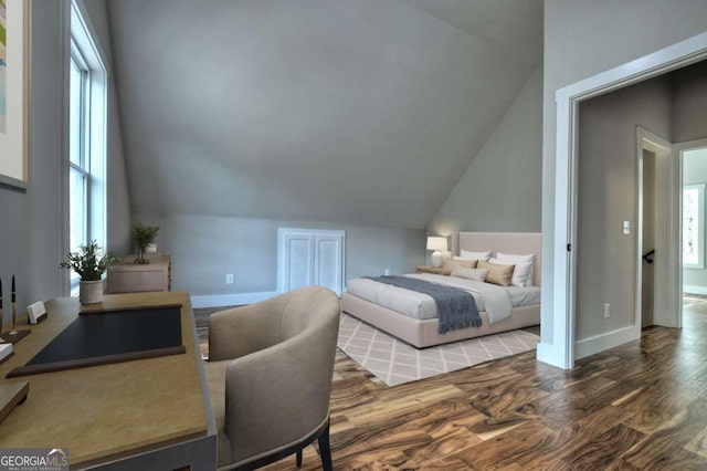 bedroom with vaulted ceiling, baseboards, and wood finished floors