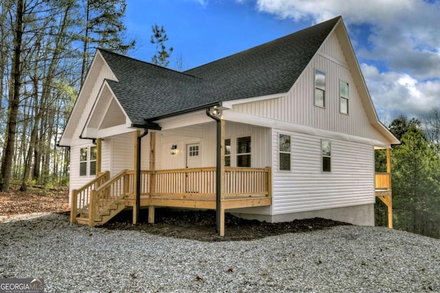 back of property with a shingled roof and a porch