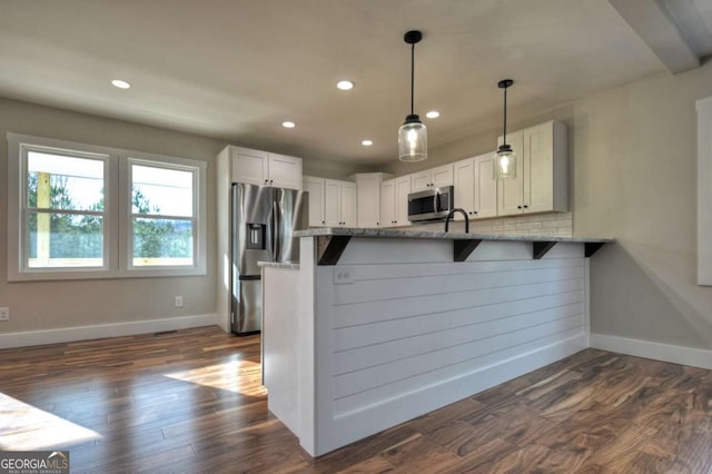 kitchen with baseboards, white cabinets, dark wood finished floors, a peninsula, and stainless steel appliances