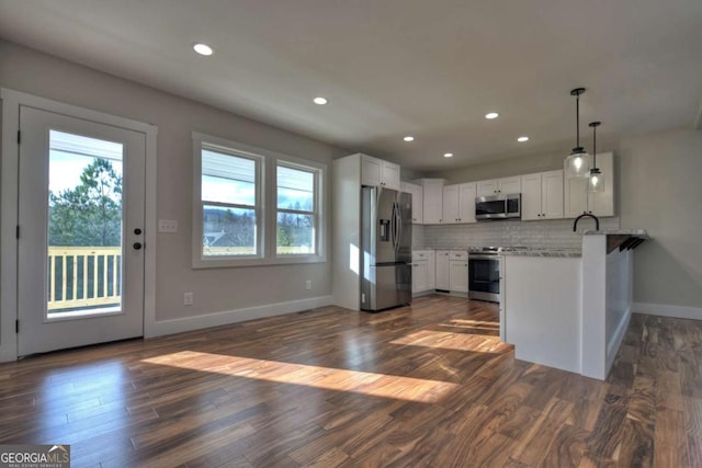 kitchen with a peninsula, appliances with stainless steel finishes, white cabinetry, and pendant lighting