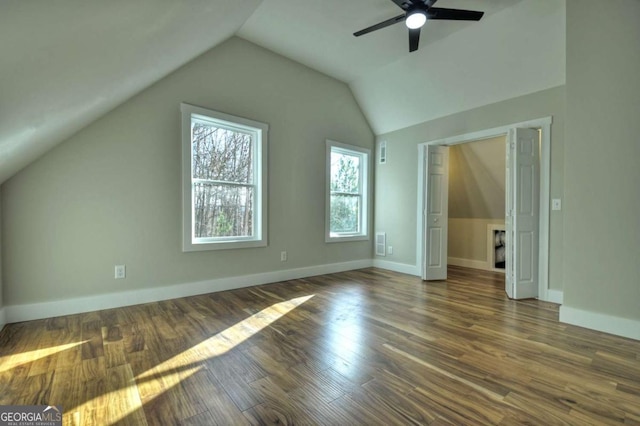 additional living space with dark wood-type flooring, lofted ceiling, ceiling fan, and baseboards