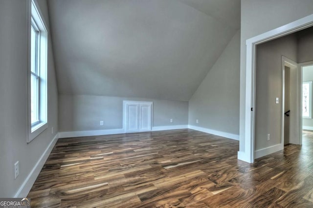 bonus room featuring lofted ceiling, dark wood-style flooring, and plenty of natural light