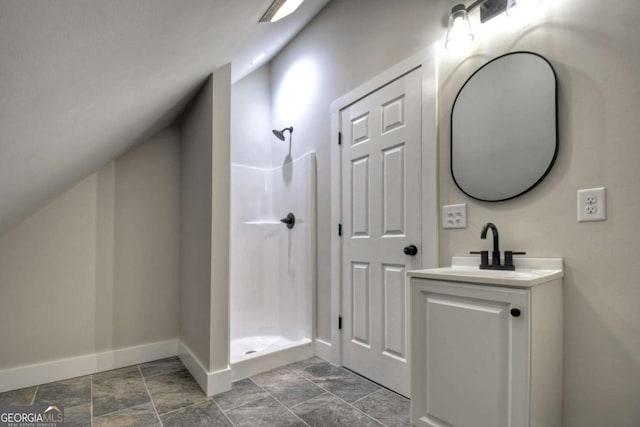 full bathroom featuring vaulted ceiling, a stall shower, vanity, and baseboards