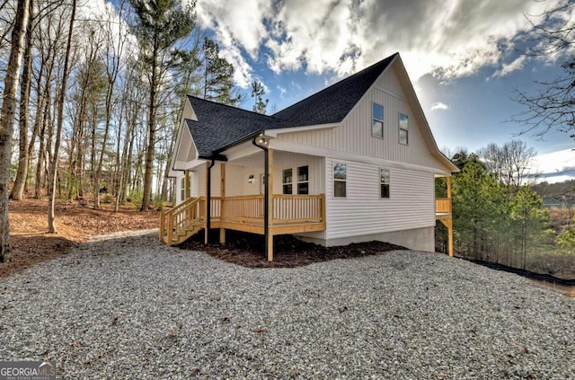 view of side of property featuring driveway, covered porch, and roof with shingles