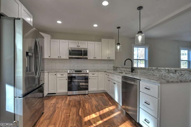 kitchen with stainless steel appliances, white cabinets, a sink, and a peninsula