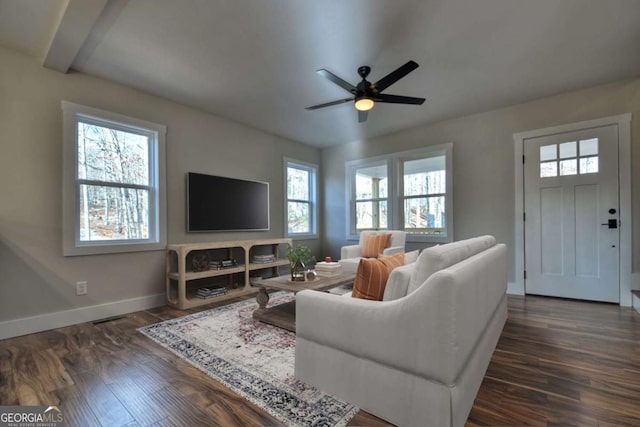 living area featuring dark wood-type flooring, ceiling fan, and baseboards