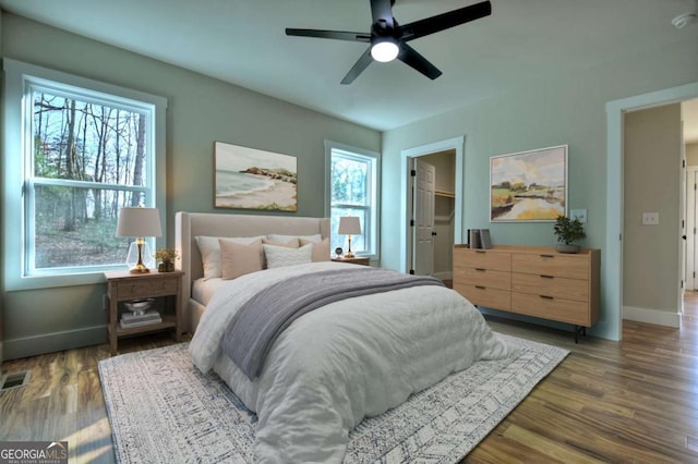 bedroom featuring dark wood-type flooring, visible vents, baseboards, and a ceiling fan