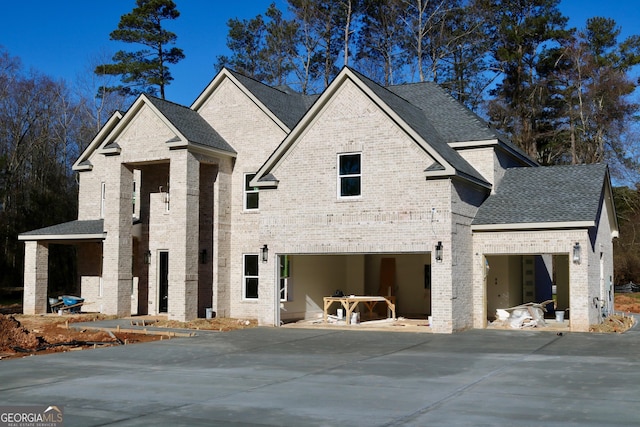 view of front of property with a shingled roof, brick siding, and a garage