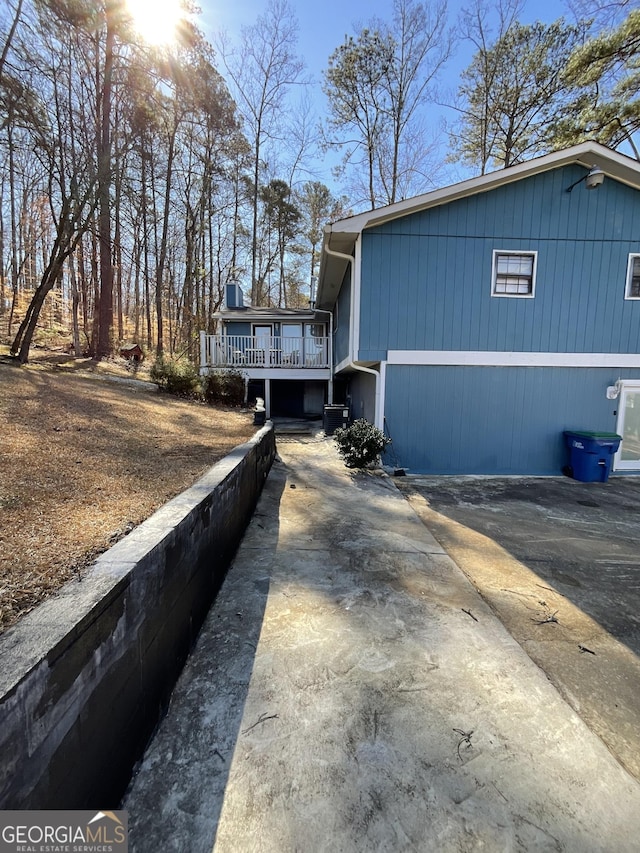 view of side of property with driveway and a deck