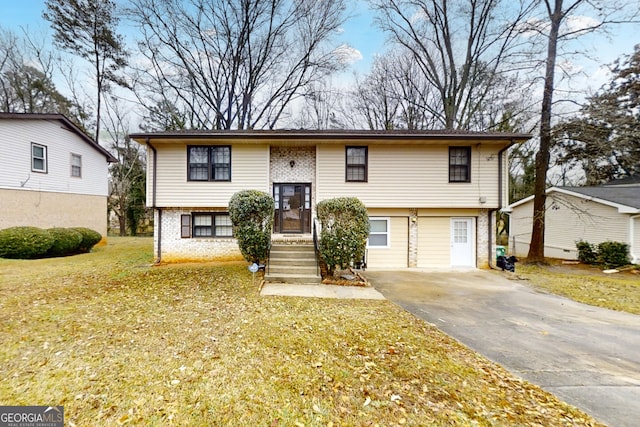 split foyer home with a garage, brick siding, driveway, and a front lawn