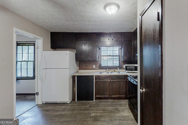 kitchen featuring light countertops, stainless steel microwave, electric range, freestanding refrigerator, and a sink