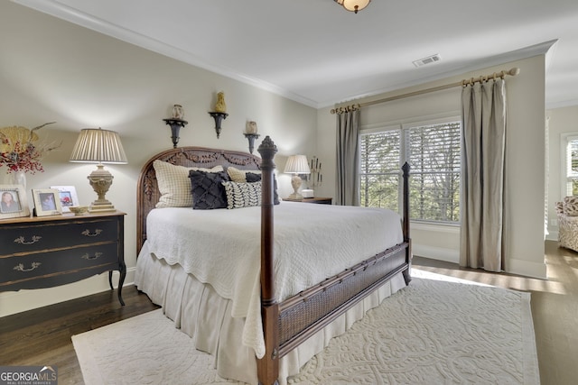 bedroom featuring baseboards, dark wood-type flooring, visible vents, and crown molding