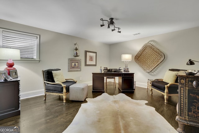 living area with dark wood finished floors, visible vents, and baseboards