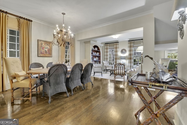 dining room featuring a notable chandelier, ornamental molding, and wood finished floors