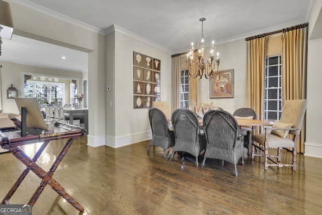 dining space featuring dark wood-type flooring, a notable chandelier, ornamental molding, and baseboards