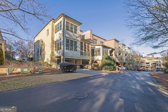 exterior space featuring a sunroom, a residential view, and stucco siding