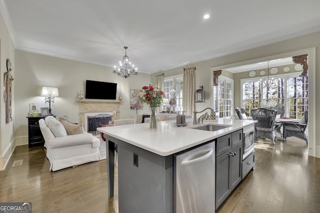 kitchen with a kitchen island with sink, stainless steel appliances, a sink, open floor plan, and light countertops