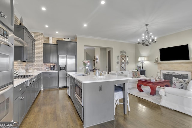 kitchen with open floor plan, light countertops, a center island with sink, and built in appliances